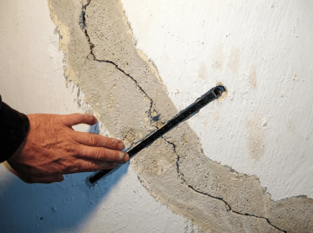 A wall with a large crack is being inspected by a professional in Raleigh, NC